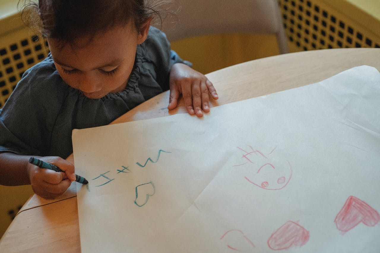 Child drawing with crayons on paper at home, expressing creativity and imagination.