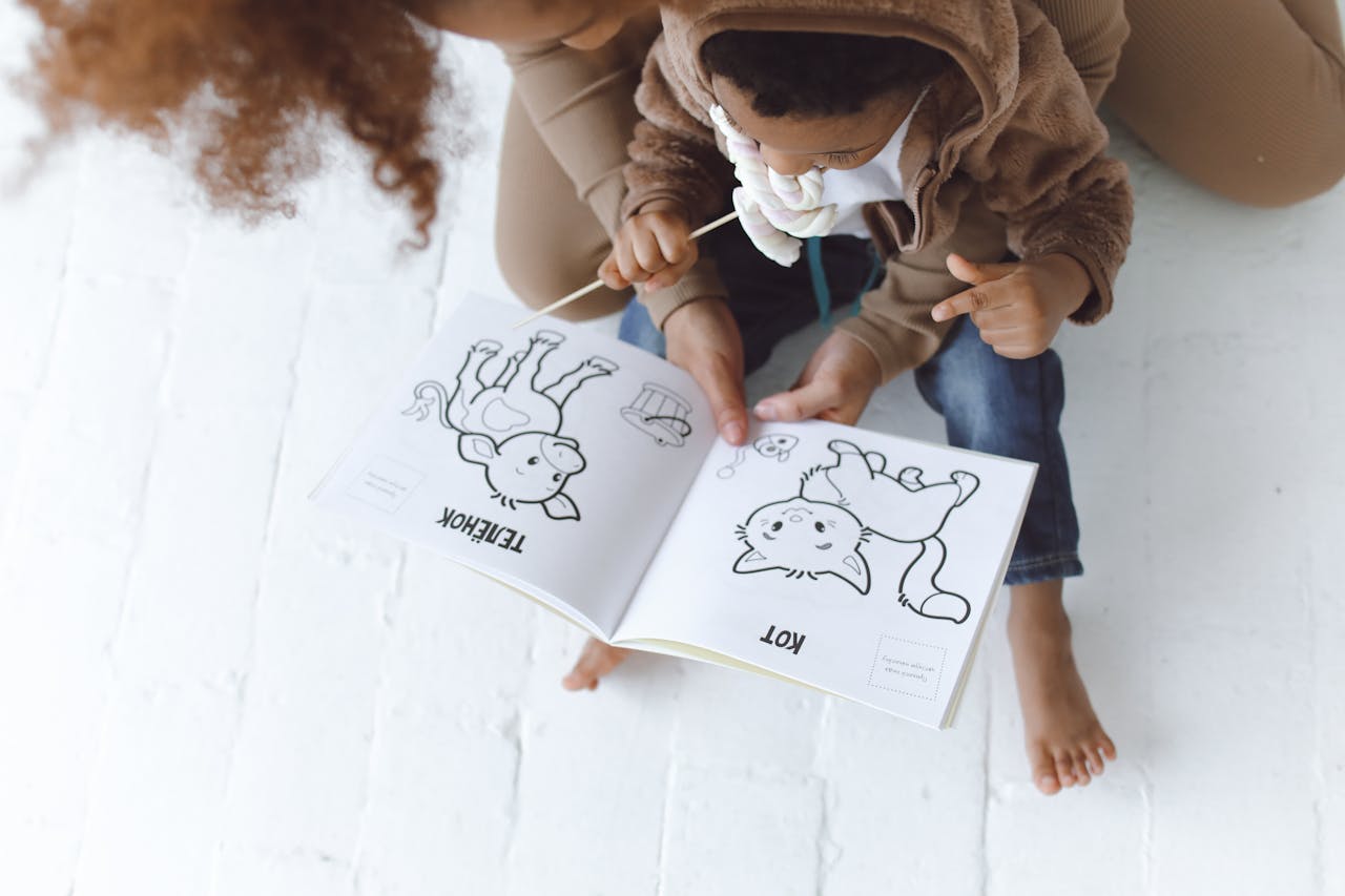Mother and child enjoying a storytelling session with a book on a white floor.